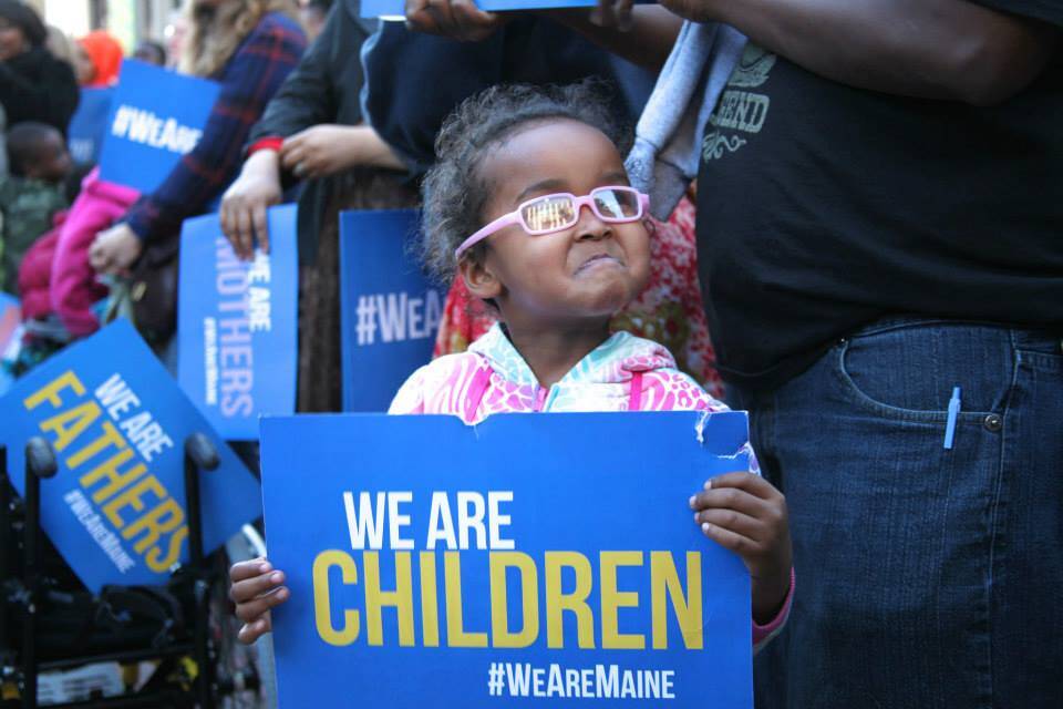 Rally participant holding "We Are Children" sign advocating for immigrant children's rights